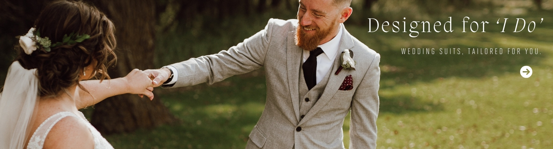 Groom in a tailored light gray wedding suit, holding the bride's hand, smiling outdoors with the caption 'Designed for I Do – Wedding Suits, Tailored for You'