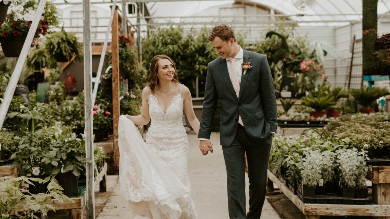 Bride and groom walking through a greenhouse, groom wearing a custom green suit.